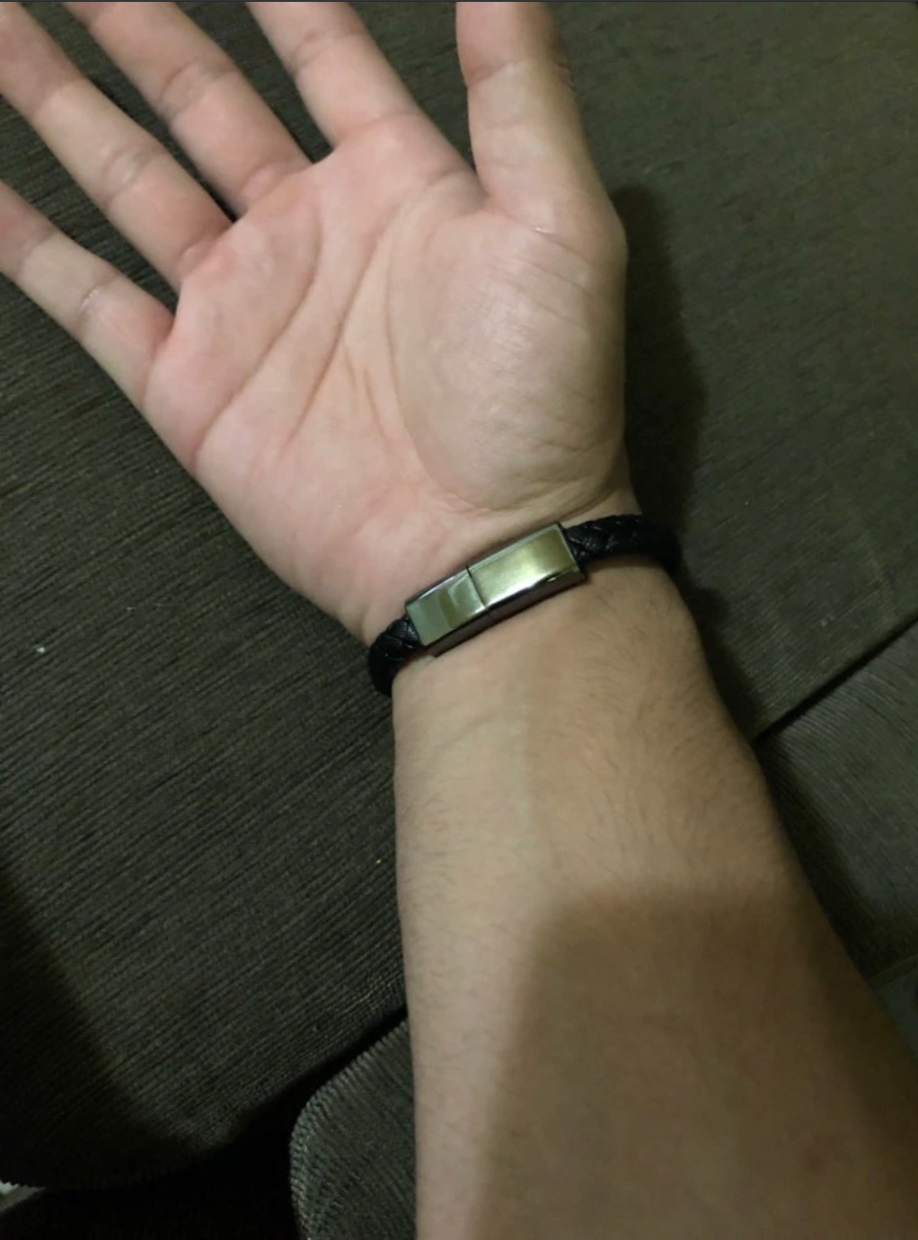 Black braided bracelet worn on a wrist